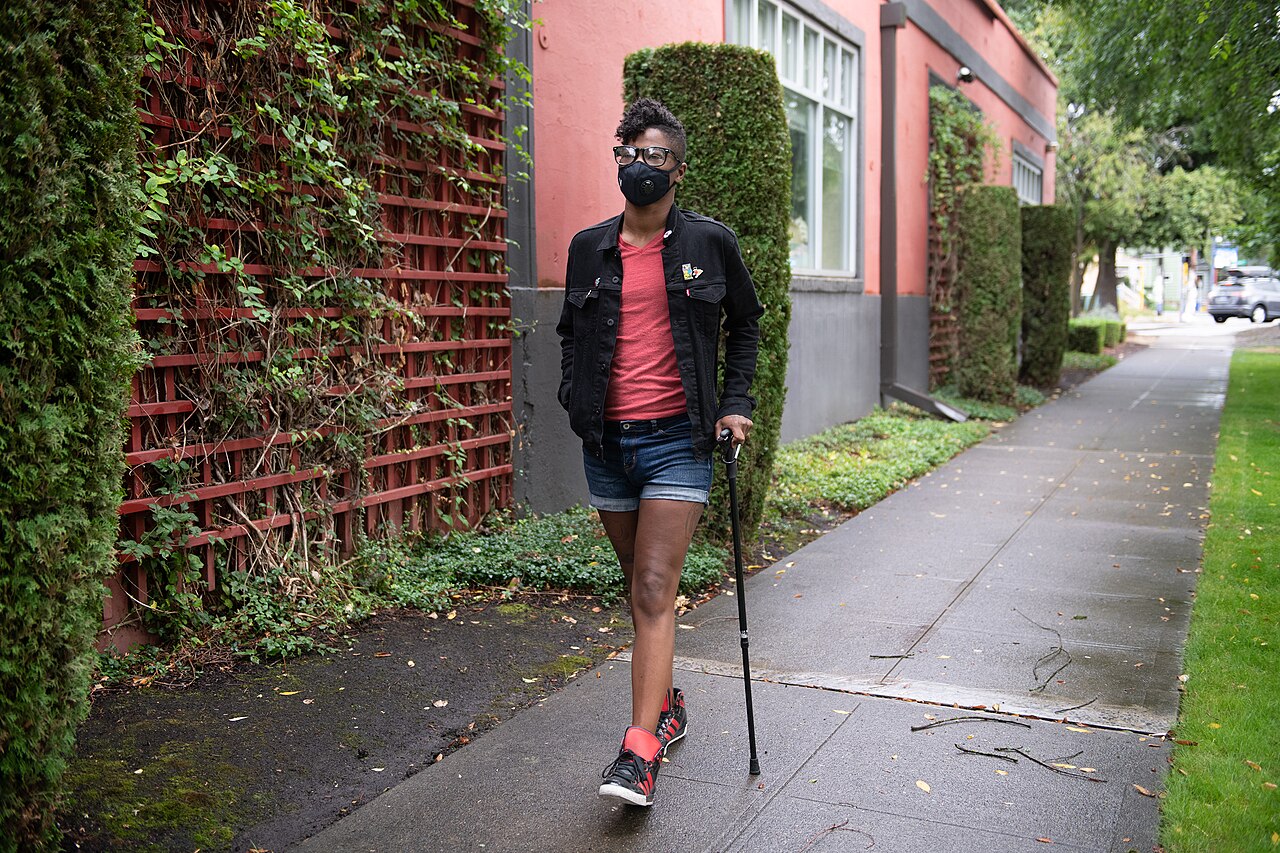 Participant using a cane and walking independently outdoors